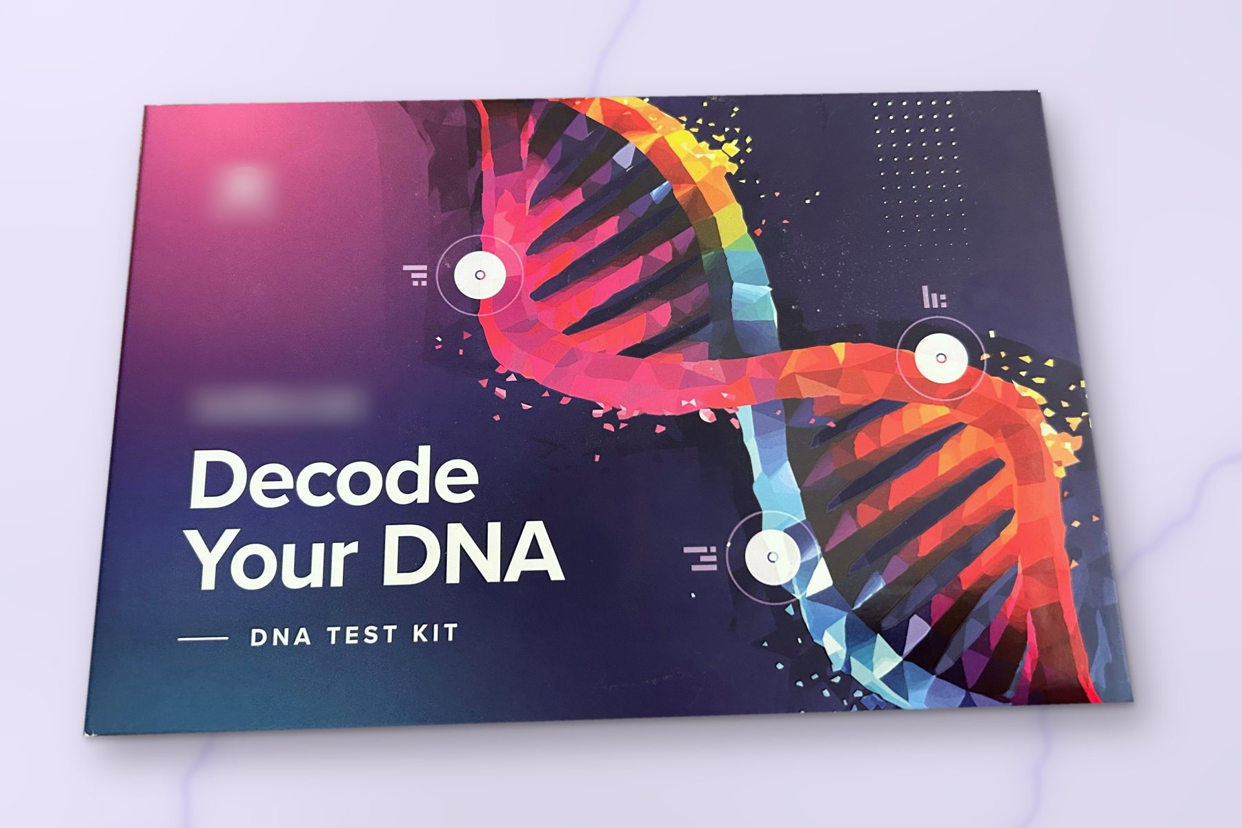 A DNA test kit box on a lavender marble surface, with the brand name blurred