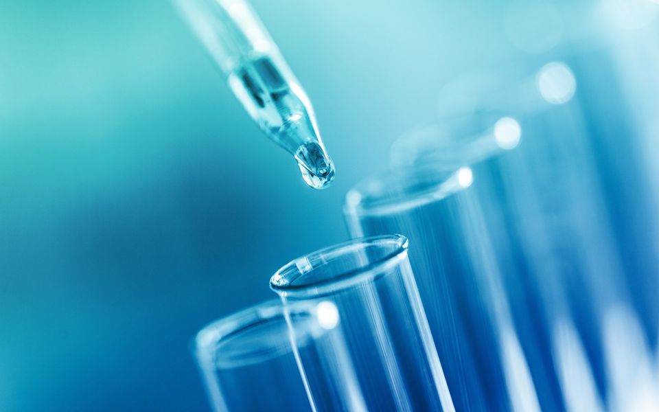 A pipette dropping a sample into test tubes